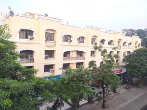 un gran edificio blanco con árboles delante de él en Hotel Ashok Tuliip Bhiwandi, en Thane