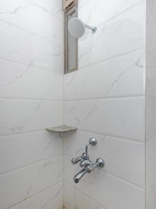 eine Dusche im Bad mit weißen Marmorwänden in der Unterkunft Hotel Ashok Tuliip Bhiwandi in Thane