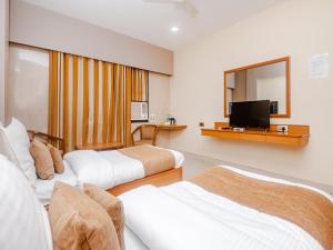 ein Hotelzimmer mit 2 Betten und einem Flachbild-TV in der Unterkunft Hotel Ashok Tuliip Bhiwandi in Thane