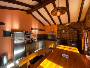 uma cozinha com uma mesa de madeira e um frigorífico de aço inoxidável em La Indefinida em Toranzo