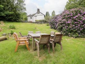 a wooden table and chairs in a yard with flowers at Hall Bank Cottage in Rydal