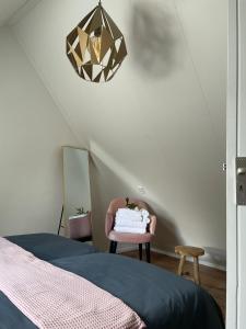 een slaapkamer met een bed, een stoel en een kroonluchter bij Charmant, ontspannen Molenzicht in Ootmarsum