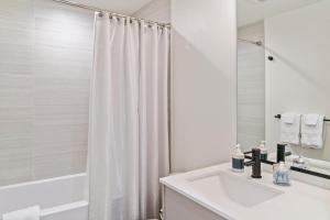 a white bathroom with a sink and a shower at Modern apartment near light rail in Seattle