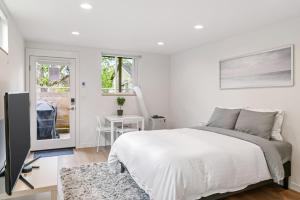 a white bedroom with a bed and a television at Modern apartment near light rail in Seattle