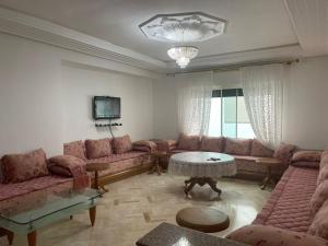 ein Wohnzimmer mit Sofas, einem Tisch und einem TV in der Unterkunft Apartment soultana in Tangier