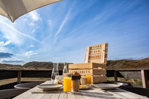 a wooden table with a glass of orange juice on it at Strandstudio's Camperduin in Schoorl