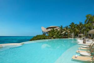 a swimming pool with lounge chairs and the ocean at Impression Isla Mujeres by Secrets - Adults Only - All Inclusive in Isla Mujeres