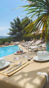 - une table avec des assiettes et de l'argenterie à côté d'une piscine dans l'établissement Hotel & Appartements Acqua Dolce, à Porticcio