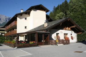 a large white building with flowers in a parking lot at Elga Residence - Relax in Alta Valtellina - Bormio in Valdisotto