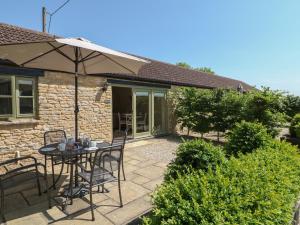 a patio with a table and chairs and an umbrella at Ewecub Barn in Burford
