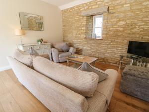 uma sala de estar com um sofá e uma televisão em Ewecub Barn em Burford
