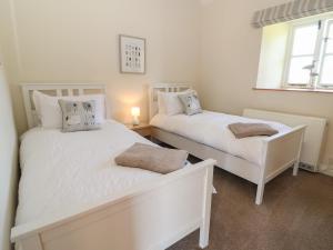 Duas camas brancas num quarto com uma janela em Ewecub Barn em Burford