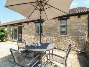 a table with an umbrella in front of a house at Nutchat Barn in Burford