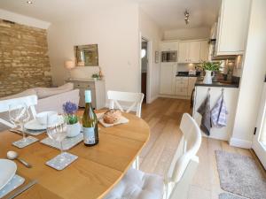a dining room and kitchen with a table with a bottle of wine at Nutchat Barn in Burford