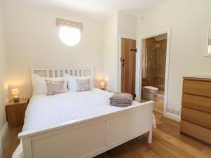 um quarto branco com uma grande cama branca com almofadas em Nutchat Barn em Burford