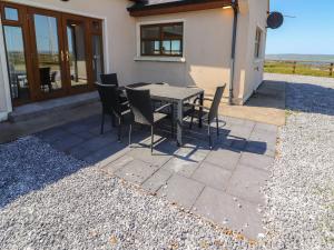 a patio with a table and chairs in front of a house at Lackamore in Lahinch