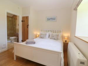 a white bedroom with a white bed and a bathroom at Saddlebacks Barn in Burford