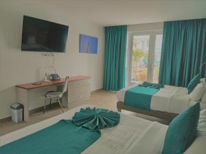 ein Hotelzimmer mit 2 Betten, einem Schreibtisch und einem TV in der Unterkunft Captain Don's Habitat in Kralendijk