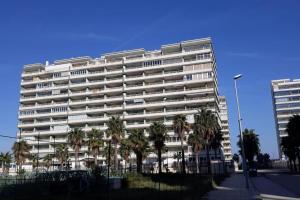 ein großes weißes Gebäude mit Palmen davor in der Unterkunft Apartamento en urbanización lujo in Tavernes de la Valldigna