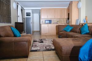 sala de estar con 2 sofás marrones y cocina en Hidden retreat in Kensington, en Johannesburgo