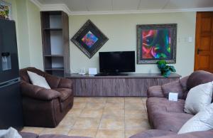 a living room with two couches and a flat screen tv at Hidden retreat in Kensington in Johannesburg