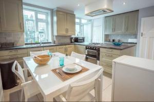 a kitchen with a white table and white chairs at 4 Bedroom in Finchley Road in London