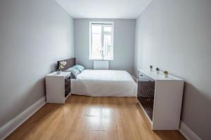 a white bedroom with a bed and a window at 4 Bedroom in Finchley Road in London