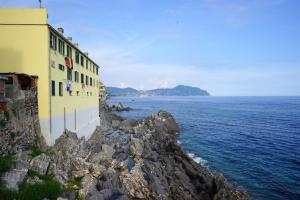 a building on a rocky cliff next to the ocean at Cà de Mâ Ω Sea Front Apartment in Genoa