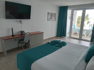 um quarto com uma cama, uma secretária e uma televisão em Captain Don's Habitat em Kralendijk