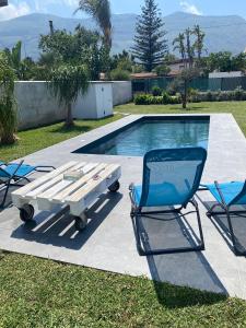 2 sedie e un tavolo da picnic accanto alla piscina di Villa Egiza con piscina e accesso diretto al mare a Carini