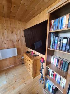 um quarto com uma televisão e uma estante de livros com livros em Burtscha Lodge im Sommer inklusive der Gästekarte Premium em Bürserberg