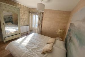 - une chambre avec un grand lit et un miroir dans l'établissement Charming little house with exposed stonework, à Luc-sur-Mer