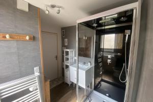 La salle de bains est pourvue d'un lavabo et d'une douche en verre. dans l'établissement Charming little house with exposed stonework, à Luc-sur-Mer
