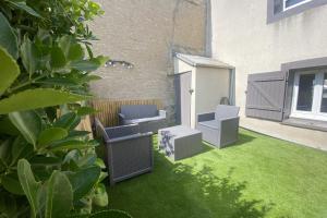 d'un jardin avec deux chaises et une pelouse. dans l'établissement Charming little house with exposed stonework, à Luc-sur-Mer