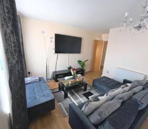 a living room with two blue couches and a tv at Keniji Luxury 2 Bed Apartment in Milton Keynes