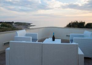 una mesa con una botella de vino y sillas en el balcón en Perla Marina, en Marina di Modica