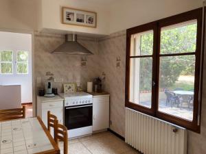 eine Küche mit einem Herd, einem Tisch und einem Fenster in der Unterkunft Villa l’oliveraie in Sanary-sur-Mer