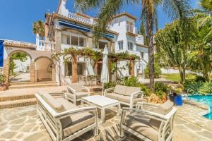 une maison avec des chaises, une table et une piscine dans l'établissement ARCADIA - AVENIDA 28 De LAS ADELFAS 29680 ESTEPONA, MALAGA, à Estepona