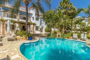 une piscine devant une maison avec des palmiers dans l'établissement ARCADIA - AVENIDA 28 De LAS ADELFAS 29680 ESTEPONA, MALAGA, à Estepona