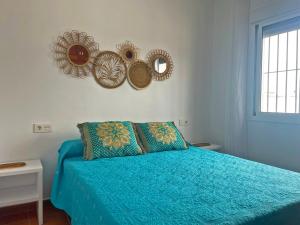 een slaapkamer met een blauw bed en spiegels aan de muur bij Villa Nostos - Ole Solutions in Conil de la Frontera