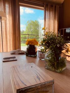 two vases with flowers on a table in front of a window at Faire une pause avec le temps in Thimister