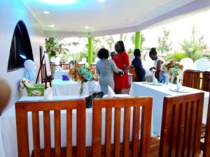 un grupo de personas de pie alrededor de las mesas con flores en Palm Star Motel en Fort Portal