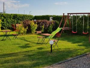 a playground with a slide and picnic tables in the grass at Kwatery Mielenko Patraj in Mielenko