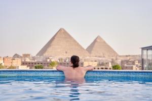 a man in a swimming pool looking at the pyramids at New Pyramid Front Hotel in Cairo