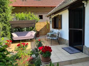 a patio with a couch and a table and flowers at CSAOL Apartman ház in Velence