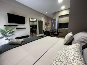 a bedroom with a large white bed with a tv on the wall at Urban Gem by Homebrain in Alexandroupoli
