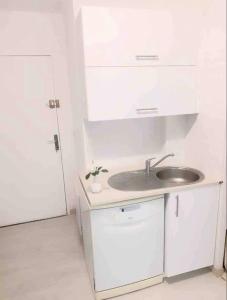 a white kitchen with a sink and a door at Agréable studio (2) 27m2 Terrasse, Parking, Piscine in Saint-Laurent-du-Var