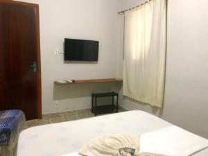 a bedroom with a bed and a tv on the wall at Bálsamo Hotel Marília in Marília