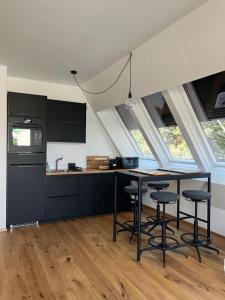 una cocina con armarios negros, mesa y taburetes en MiasApp en Viena