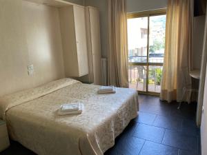 una camera d'albergo con un letto e due asciugamani di Hotel La Perla a Riva del Garda